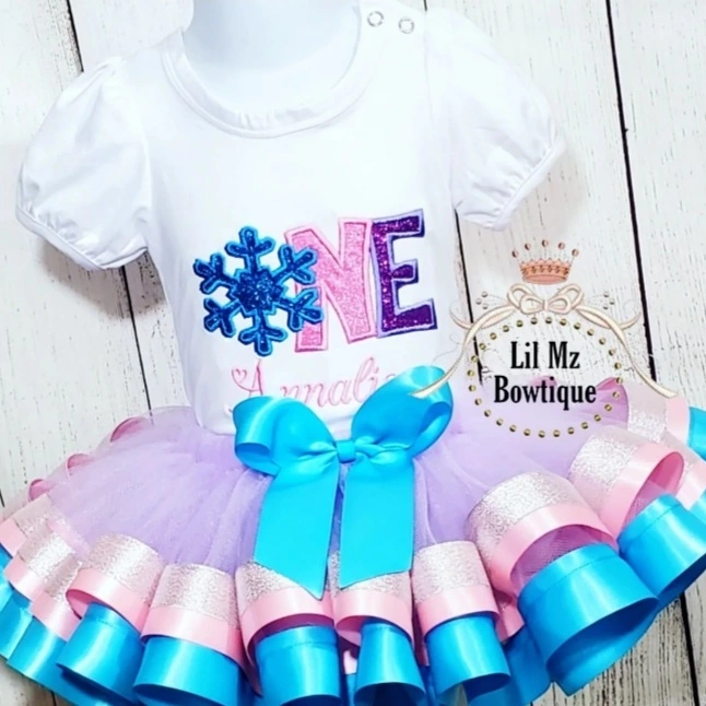 Snow Flake 1st Birthday Tutu outfit with white embroidered top and purple tutu skirt with blue and pink ribbon trim and blue bow
