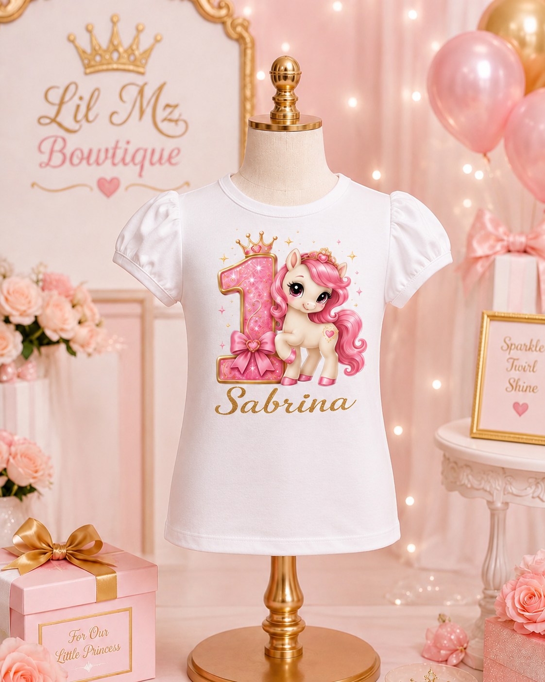 White t-shirt with a unicorn design and text on a mannequin against a pink-themed background with balloons and flowers.