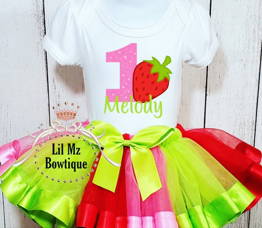 Strawberry tutu outfit for toddler with bright green and red tulle skirt and personalized white shirt with strawberry and number one design