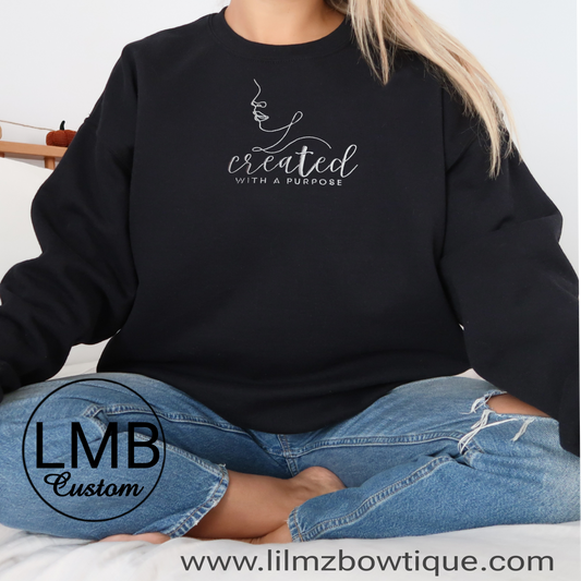 black unisex sweatshirt with embroidered "created with a purpose" text and abstract face design